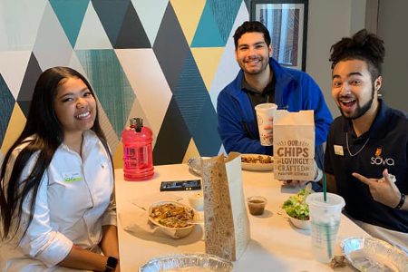 Three residents sitting at a table, eating, smiling for the camera